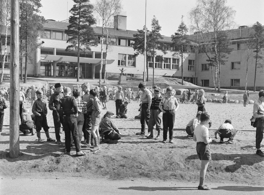 Lapsia koulun pihalla mustavalkoisessa valokuvassa.