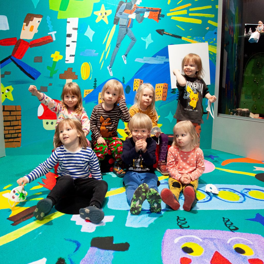 Valokuvassa riemuitsevia lapsia Museo Leikin Ruutuhyppy-näyttelyssä.