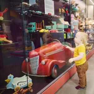 Lapsi ihailee autoa Museo Leikin Leikin laboratorio näyttelyssä.