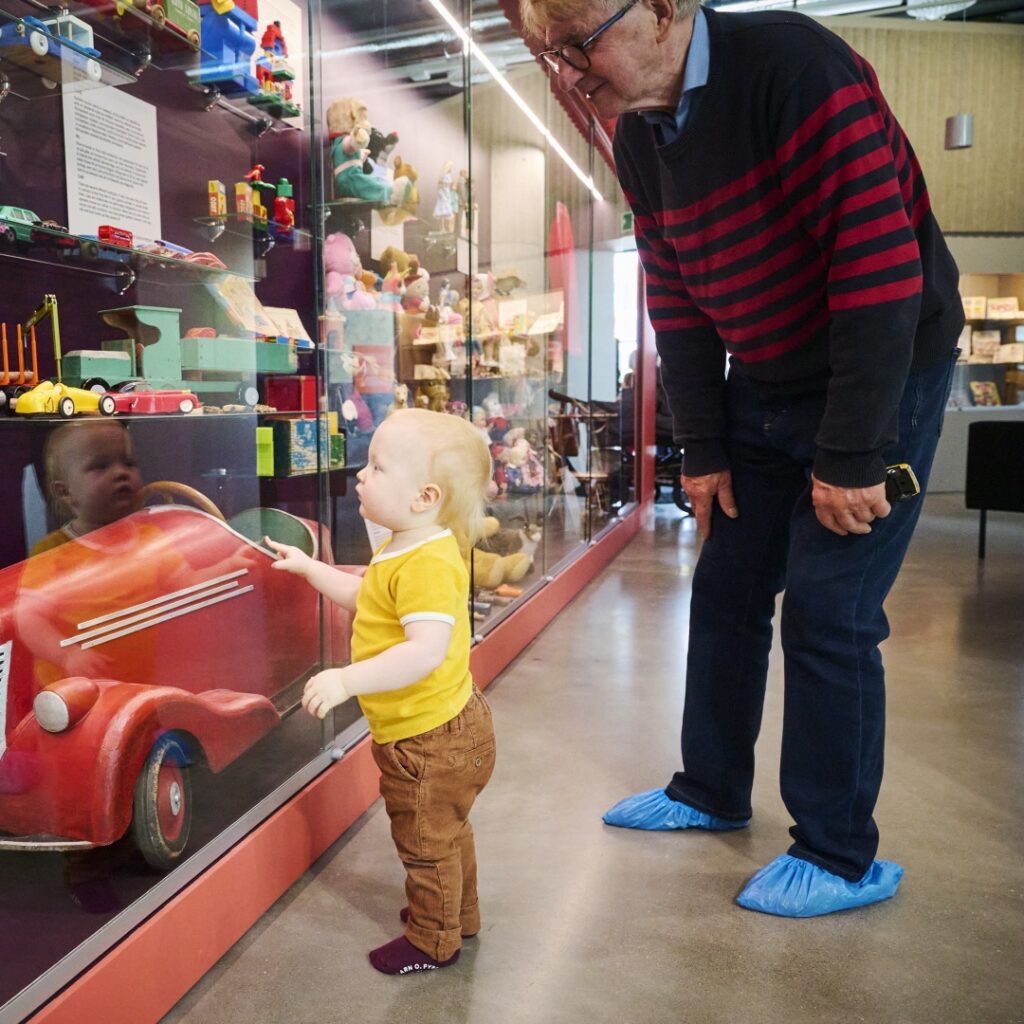 Isoisä ja pikku-poika katsovat esineitä vitriinissä.