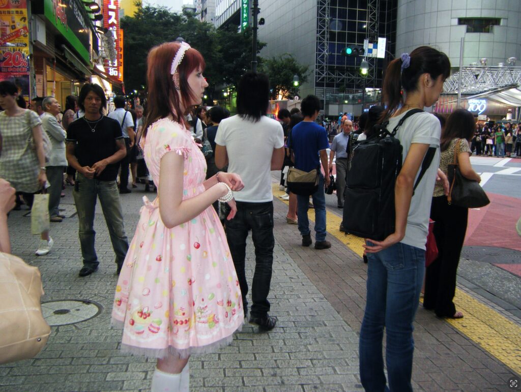 Nuori nainen pastellin värisessä asussa kadulla väkijoukossa.