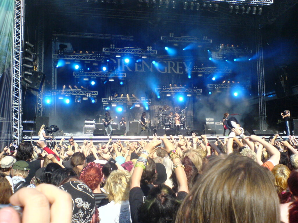 Rock-bändi Dir en Grey lavalla, etualalla yleisön päitä ja käsiä.